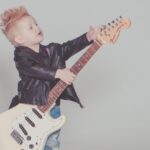 NIño pequeño sosteniendo una guitarra eléctrica