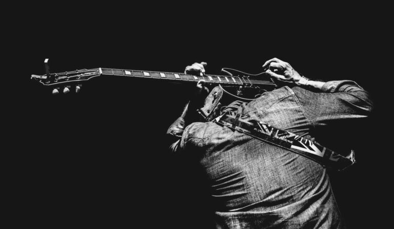 Hombre tocando la guitarra en su espalda